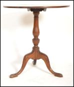 A 19th century mahogany circular tilt top wine / occasional table being raised on tripod splayed leg