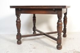 A 1930's oak draw leaf refectory dining table being raised on turned legs united by stretcher having