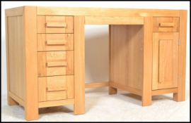 A contemporary solid oak twin pedestal desk, having an arrangement of nine drawers fitted with