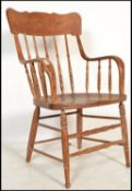 A 20th century American Windsor style country oak armchair raised on turned legs united by stretcher