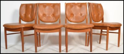 A set of 4 mid century retro teak wood and faux tan leather dining chairs. Raised on shaped legs
