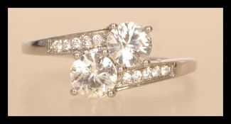 A hallmarked 9ct white gold crossover ring having two large brilliant cut white stones with white