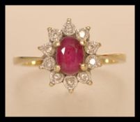A hallmarked 9ct gold ruby and diamond cluster ring having a central faceted ruby with a halo of