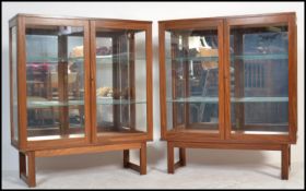 A pair of vintage retro 20th century teak wood glass bookcase display cabinets being raised on