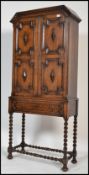 A 1920's Jacobean revival oak barleytwist cabinet bookcase on stand. Raised on bell pad feet with