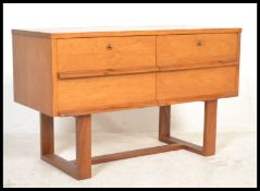 A 1970's teak wood chest of drawers being raised on square stile legs with returns having a bank