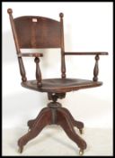 A Victorian 19th century oak Industrial office swivel desk chair - captains chair being raised on