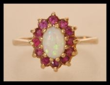 A hallmarked 9ct gold opal and ruby ring having a central opal cabochon with a halo of rubies.