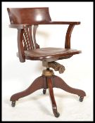 A 1930's oak office desk chair having a leather panel to the seat, pierced splat, bowed arms, four