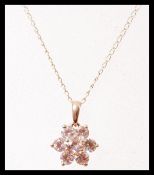 A 14ct gold flower head pendant set with five white sapphires on a gold chain, having a spring