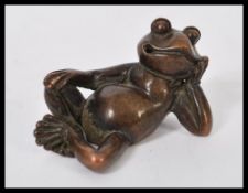 An early 20th century bronze figurine of a cheeky reclining toad. Makers stamps to base.