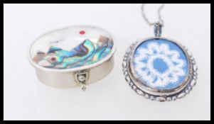 A Mexican silver pill box with mother of pearl scene of mountains and a bird to the lid. Also with a