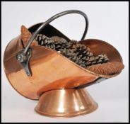 An Early 20th Century copper coal scuttle, set on a pedestal circular base with a fitted brass