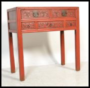 A Chinese mid Qing dynasty red lacquered three alter table, having an arrangement of five ornately