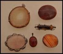 A selection of agate brooches and pendants to include a large stone pendant, a red stone pendant,