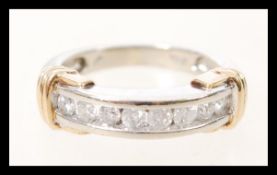 A stamped 10k white gold ring having 8 channel set brilliant cut diamonds, and yellow gold