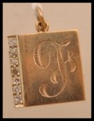 A yellow metal tests as 9ct gold necklace pendant having a monogrammed front with seven inset