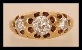 A stamped 18ct gold and diamond ring set with three old cut diamonds in a pierced decorative head.