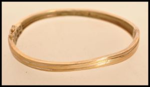 A yellow metal but tests as 9ct gold bangle bracelet having a hidden clasp AF with fold over
