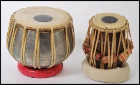 Two 20th century Indian table drums to include a polished metal cased drum and a wooden drum, both