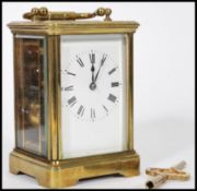 An early 20th century brass carriage clock having a white enamelled face and faceted hands, a