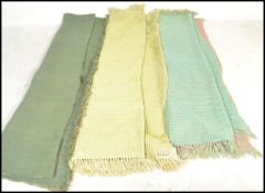 A collection of three vintage mid 20th Century waffle woollen blankets, each on light pastel