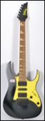 A vintage Ibanez Gio electric guitar having a black body with yellow scratch guard and black
