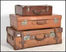 A stack of three vintage early 20th century graduating leather suit cases, each in brown leather