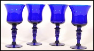 A set of four unsigned Bristol Blue glass wine goblets raised on a circular foot with knopped stem