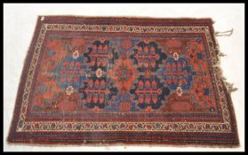 A vintage 20th Century floor rug / mat on red ground, central panel with geometric borders with