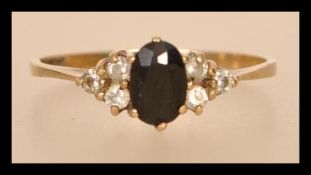 A hallmarked 9ct gold blue sapphire and white stone ring having a central faceted blue stone flanked