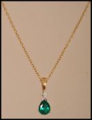 A hallmarked 9ct gold necklace chain having a 9ct gold diamond and green stone pendant. Weighs 2.5