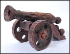 An early 20th century carved wooden large cannon raised on large wheels with geometric patterns