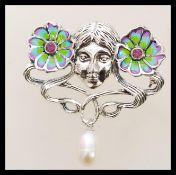 A silver Art Nouveau style plique a jour brooch in the form of a face and two flowers having a pearl