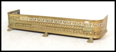 An early 19th Century Georgian brass fender kerb guard with lions paw feet and pierced vine and