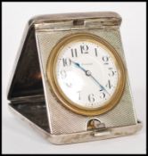 A silver 900 stamped travelling pocket watch clock having an engine turned case. The white enamel