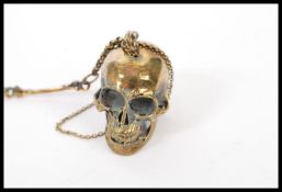 A gentleman's brass albert watch chain having an articulated skull and and skeleton detailing.
