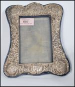 An early 20th century silver hallmarked picture frame having embossed scrolls leaves and cherubs.