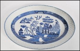 A 19th century Chinese blue and white willow pattern meat platter of large form having woven