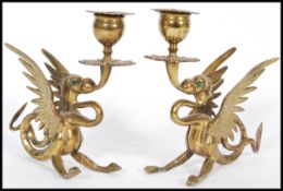A pair of late 19th century cast brass candlesticks modelled as dragons with wings raised scrolled