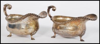A pair of early 20th century silver hallmarked sauce gravy boats raised on hood feet with acanthus