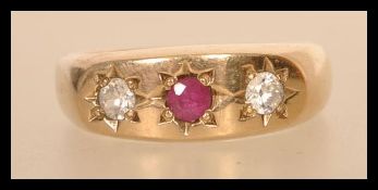 A hallmarked 9ct gold three stone ring having a central faceted red stone in star setting flanked by