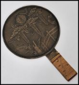 A 19th century Japanese bronze hand mirror having cane wrapped handle. The central circular mirror