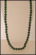 A Chinese deep green jade bead necklace consisting of over 60 circular jade beads.