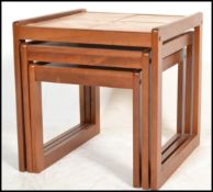 A set of three retro 20th Century tile topped teak wood neat of tables, each nest set with four