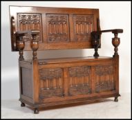 A good Jacobean revival oak monks bench settle table with fold down top and blue cushion flanked