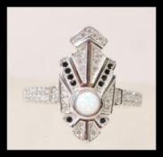 A silver and cz art deco style ring set with a central round opal and black accent stones. Size P.5.