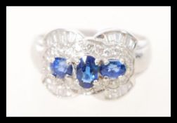 A stamped 750 white gold art deco style diamond and sapphire ring set with three central oval cut