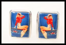 A pair of silver mens cufflinks having square enamel panels depicting the figure of a vintage pin up