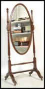 An early 20th Century Edwardian mahogany floor standing cheval mirror of oval form flanked by turned
